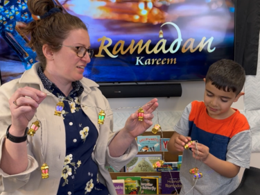 Female staff works with elementary male student decorate for Ramadan