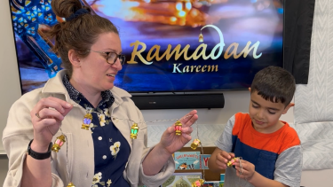 Female staff works with elementary male student decorate for Ramadan