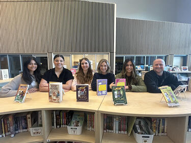 Six smiling teacher candidates standing in the library