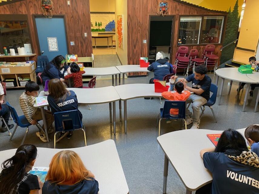 Young children reading with high school kids.