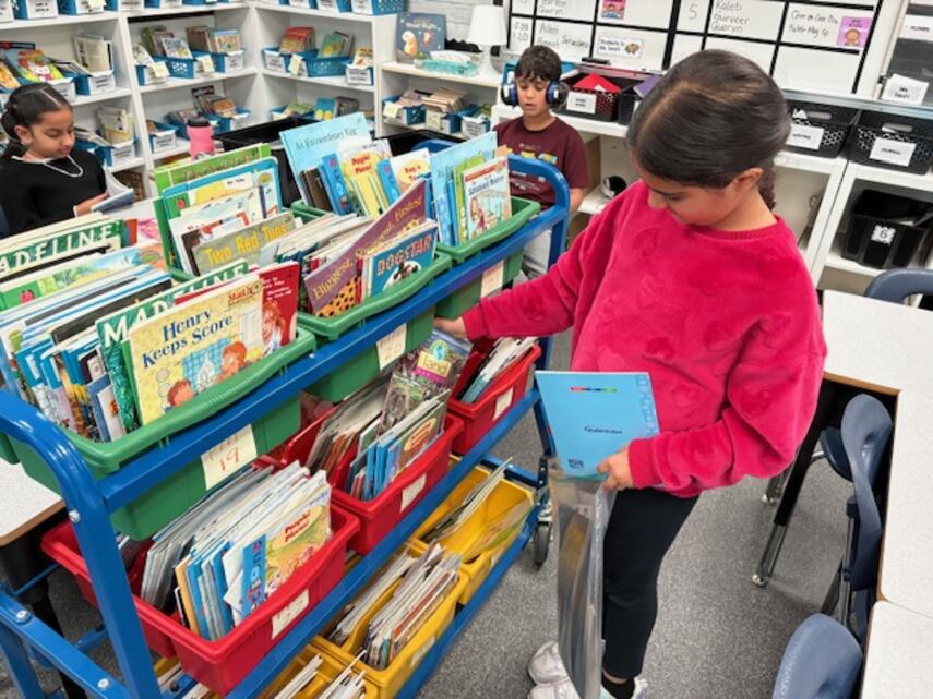 Student choosing books from a book cart.