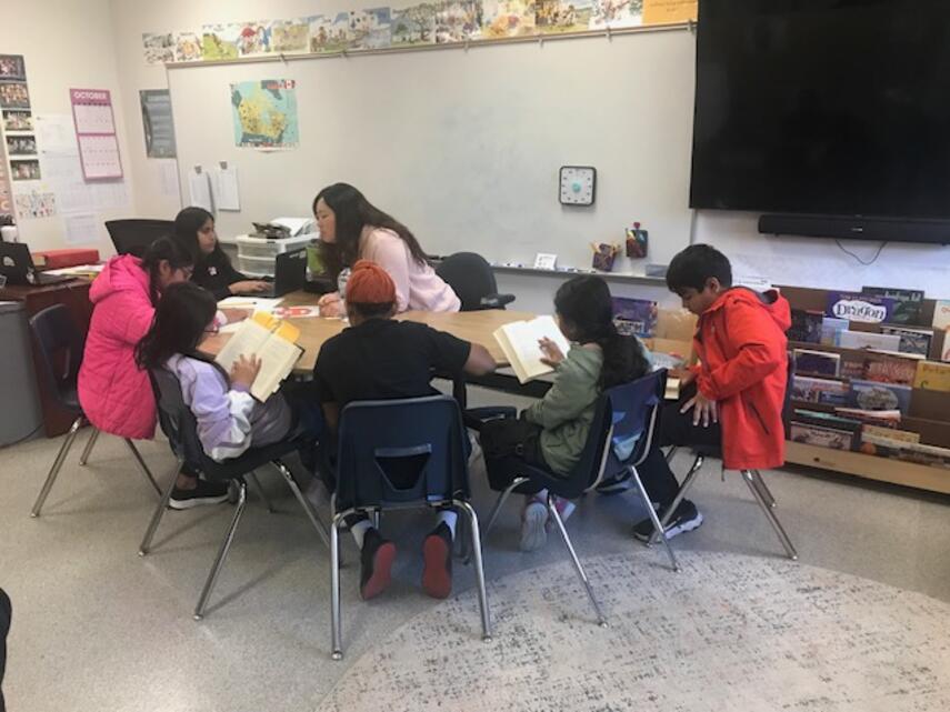 Students in at a table reading with an adult.