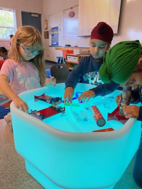 Students explore items on a glow table.