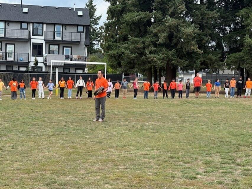 Students in a circle while someone drums in the middle.
