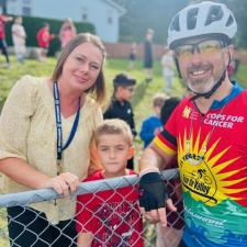 Teacher posing with student and a Cops for Cancer rider participant 